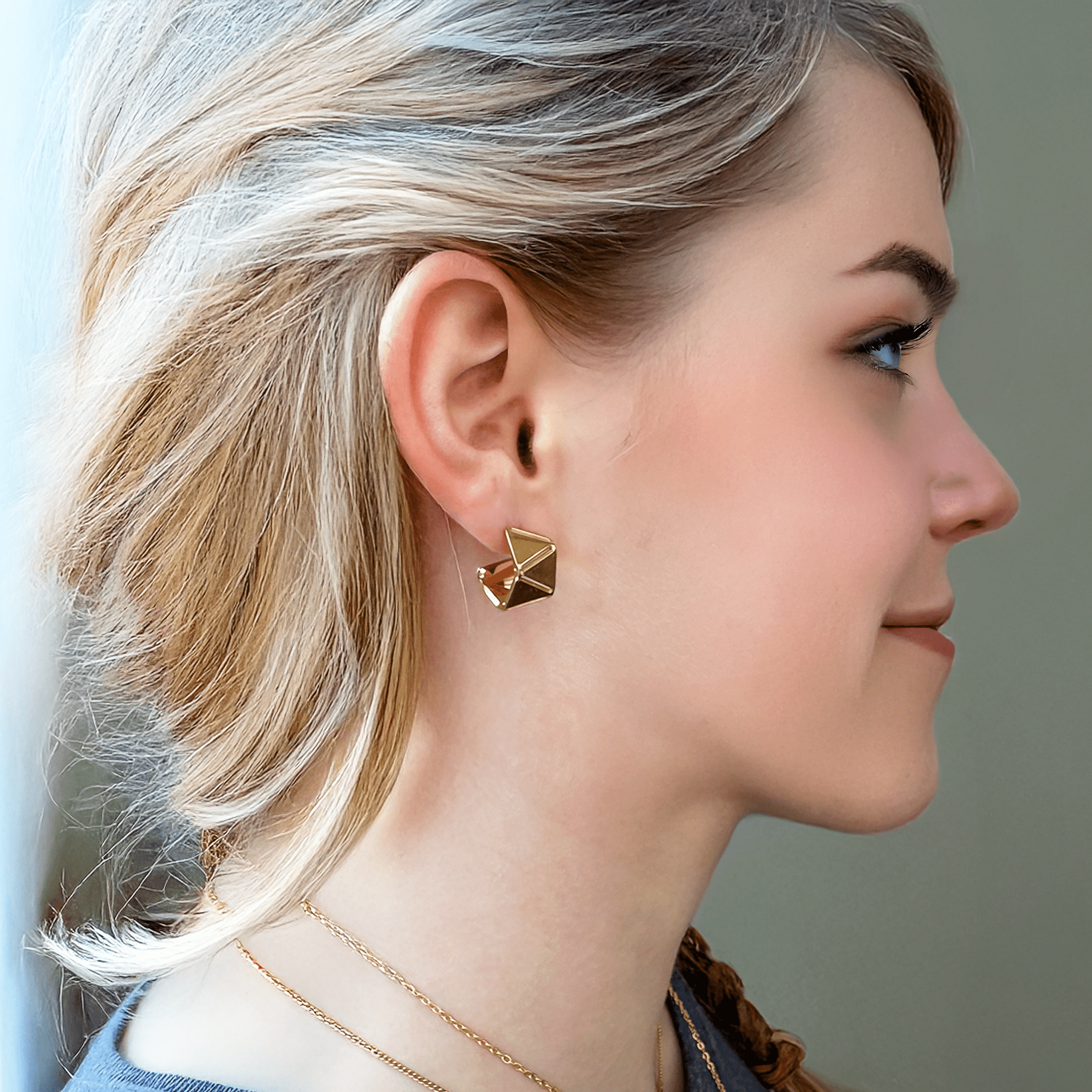 Image of gold Eliasz and Ella Euclide Huggie hoop earrings with geometric facets shimmering in soft light—15 mm stainless steel hoops with 18K gold plating.