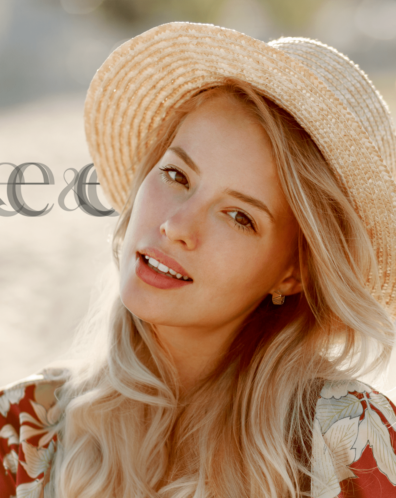 Blonde woman in a sunhat smiles softly in warm sunlight. She wears Euclide Huggie Earrings—gold, faceted, geometric hoops—paired with soft waves and a botanical print blouse. The mood is effortless and summery.