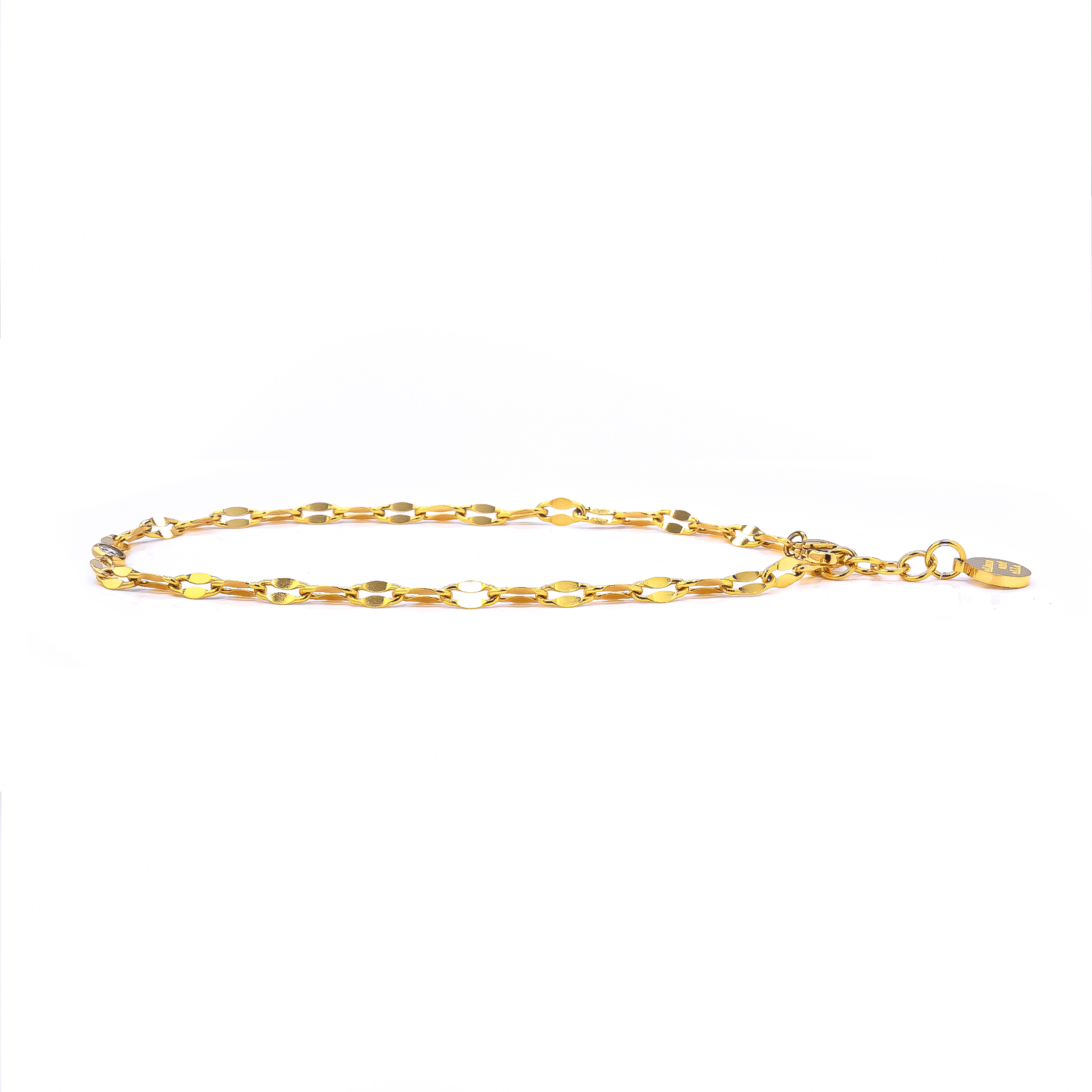 A soft, gold-tone chain with a central CZ stone is shown elegantly resting on skin, styled as both anklet and bracelet. It shimmers as the model moves gently, highlighting the chain’s flexibility and detail. Anklet.